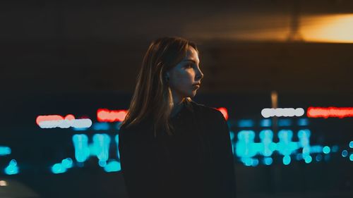 Thoughtful young woman looking away while standing at night