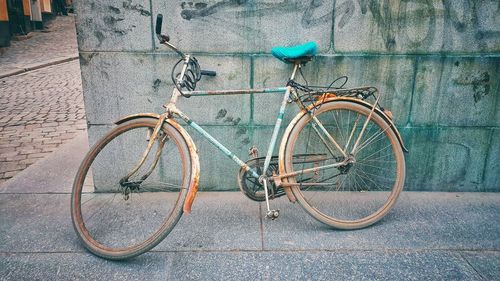 Bicycle parked on footpath by wall