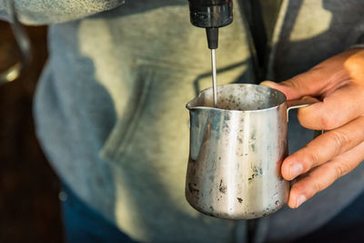 Close-up of hand pouring coffee cup