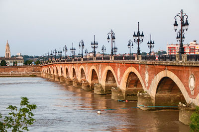 Bridge over river in city against clear sky