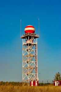 Low angle view of red tower on field against clear blue sky