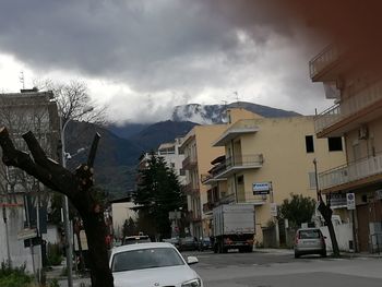 Cars on road by buildings against sky