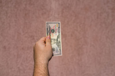 Close-up of hand holding paper against blurred background