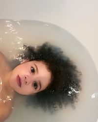 High angle portrait of cute girl lying in bathtub