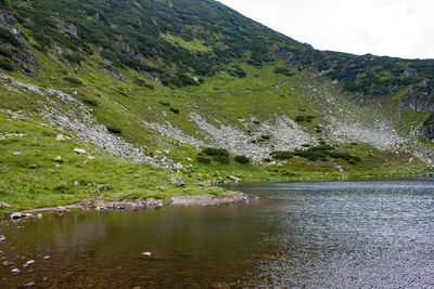 Scenic view of lake by mountain against sky