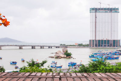 Scenic view of river by building against cloudy sky