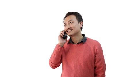 Portrait of smiling young man standing against white background