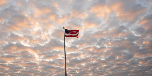 Low angle view of flag against orange sky