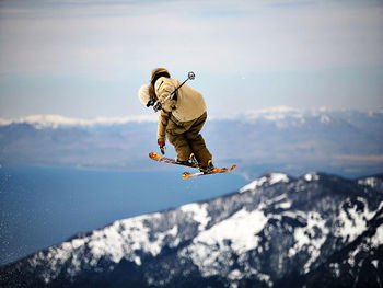 Man jumping in mountain against sky