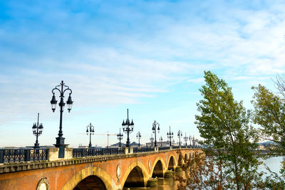 Street lights on bridge over river against sky