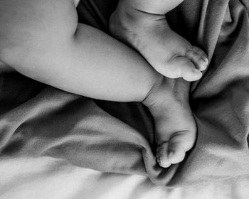 Low section of baby relaxing on bed