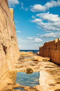 Rock formations on shore against sky