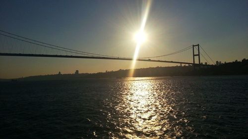 Silhouette bridge over river against sky during sunset