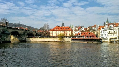 Bridge over river by buildings against sky in city