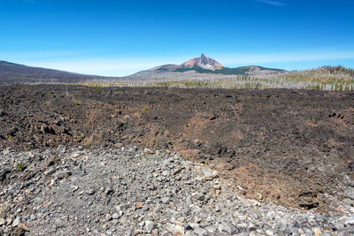 Scenic view of arid landscape against blue sky