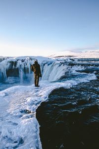 Man standing in snow against sky during winter