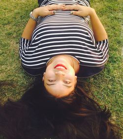 Portrait of smiling young woman lying on grassy field 