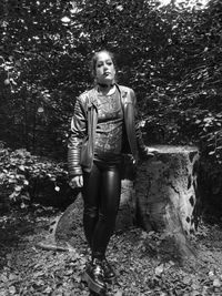 Portrait of young woman standing against trees