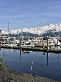 Sailboats moored at harbor against sky during winter