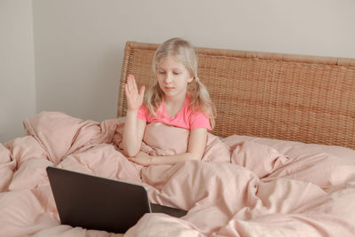 Girl raising hand and learning in virtual online school class.  homeschooling for children.