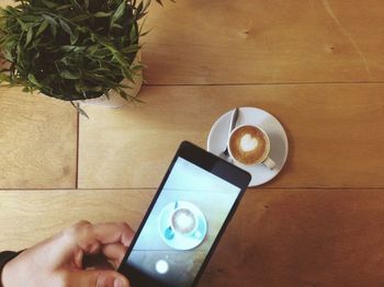 High angle view of hand holding coffee cup on table