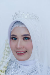 Portrait of young woman wearing hijab against white background