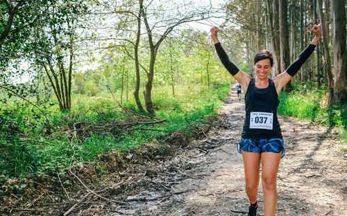 Cheerful woman exercising in forest