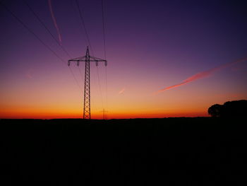 Silhouette electricity pylons on landscape against romantic sky at sunset