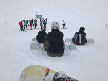 People skiing on field against sky during winter