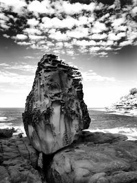 Rock formation on beach against sky