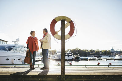 Full length of senior couple standing on pier against sky