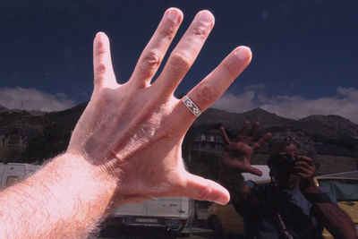 Cropped hand of man with reflection on glass while photographing