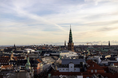 High angle view of buildings in city against cloudy sky