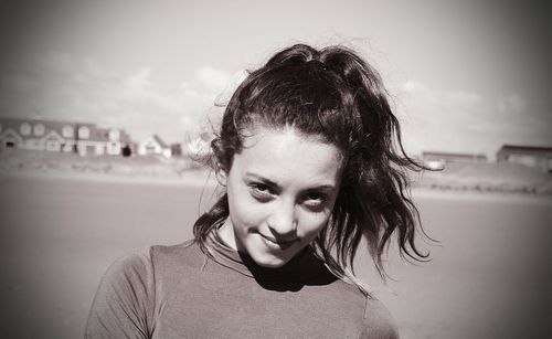 Portrait of teenage girl standing at beach against sky