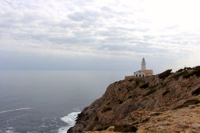 Lighthouse by sea against sky