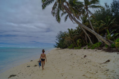 Woman walking at beach against sky