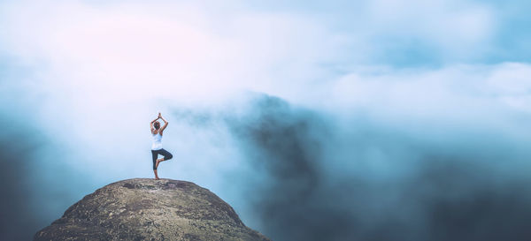 Low angle view of man standing on mountain against sky