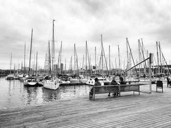 Sailboats moored at harbor against sky