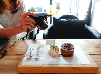 Midsection of man photographing while sitting on table at home