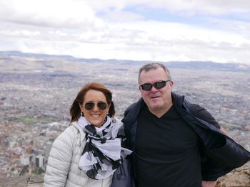 Portrait of mature couple wearing sunglasses while standing against landscape