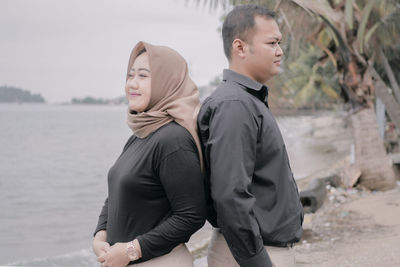 Side view of couple standing on beach