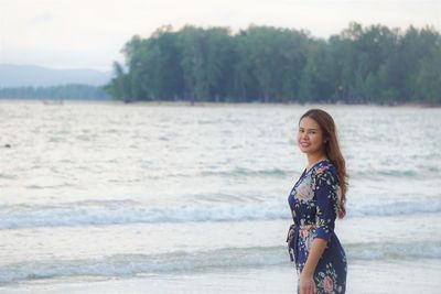 Portrait of smiling woman standing at beach