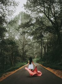 Woman sitting on road amidst trees