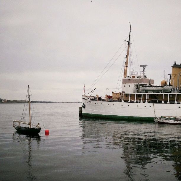 nautical vessel, water, moored, transportation, boat, mode of transport, waterfront, harbor, sky, sea, reflection, mast, lake, built structure, pier, nature, sailboat, day, outdoors, architecture