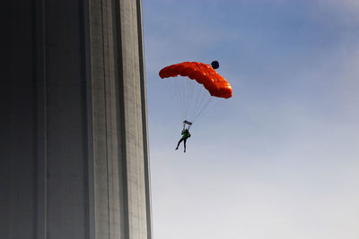 Low angle view of person flying red paraglider