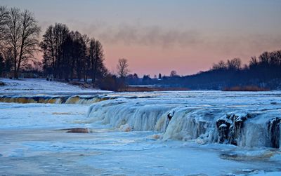 Scenic view of frozen river against sky during sunset