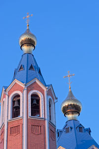 Low angle view of church roofs against clear blue sky