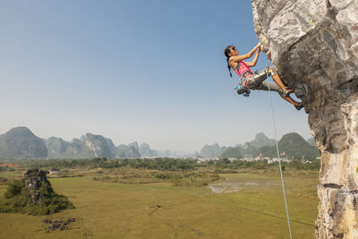 Female climber pulling up on overhanging rock in yangshuo / china