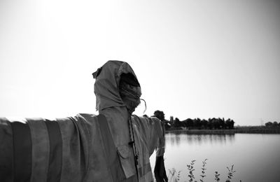 Close-up of scarecrow by lake against clear sky