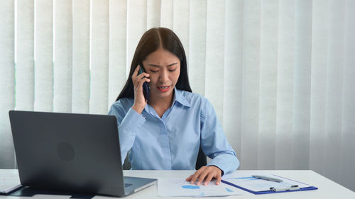 Young woman using phone on table